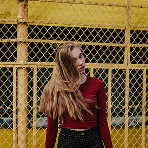 woman standing behind yellow chain link fence thumbnail