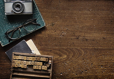 still life photography of gray camera, black framed eyeglasses and brown letter chips thumbnail