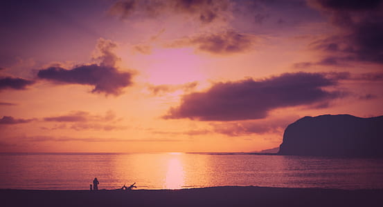silhouette of calm body of water and rock formations at golden hour thumbnail