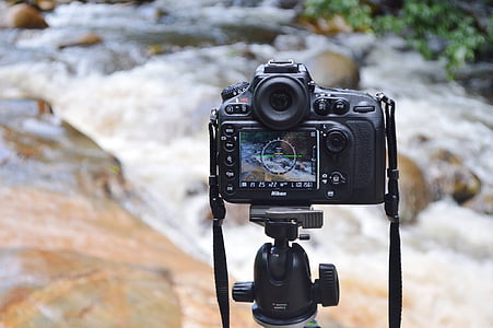 black DSLR camera taking video of flowing river thumbnail