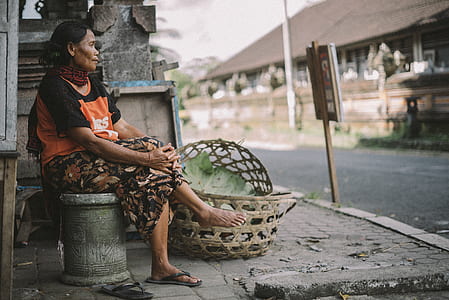 woman sitting on concrete chair facing road thumbnail