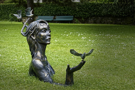 woman with bird on hand statue on green grass field during daytime thumbnail
