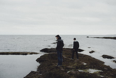 man wearing black jacket and blue jeans surrounded by body of water thumbnail