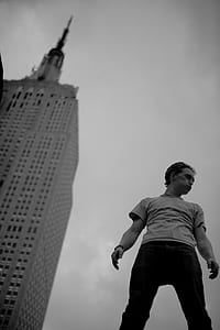 grayscale photography of a man standing near building thumbnail