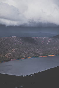 lake surrounded by mountains under cloudy sky thumbnail