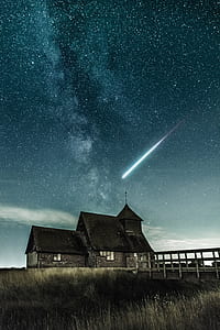 comet in sky above black concrete house thumbnail