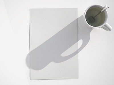 shadow of mug with tablespoon on white printer paper thumbnail