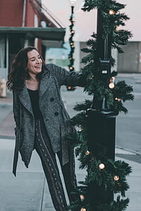 woman holding on black utility pole near road during daytime thumbnail