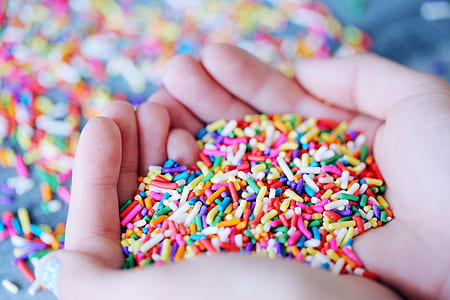 person holding multicolored candy sprinkles thumbnail