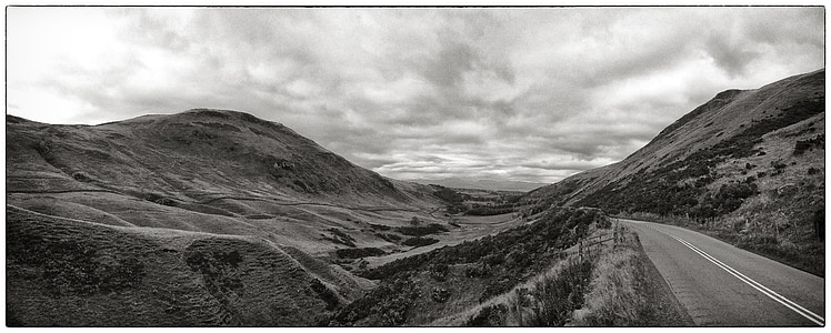 grayscale photo of road beside mountains thumbnail