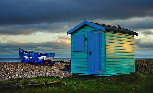 blue and green shed on seashore beside boat thumbnail