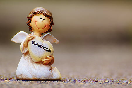closeup photography of white angel figurine carrying heart thumbnail