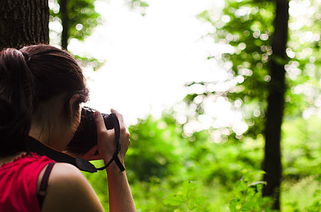 selective focus photography of woman pointing camera at trees thumbnail