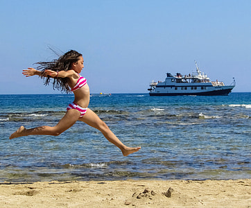 candid photography of girl jumping on seashore thumbnail