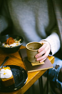 Person Holding Mug on Top of Brown Book thumbnail