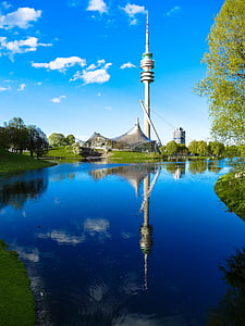 white tower near body of water and trees during daytime thumbnail