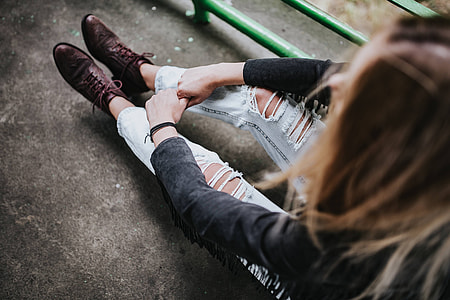 Blonde woman in a black jacket and ripped jeans by a green handrail thumbnail