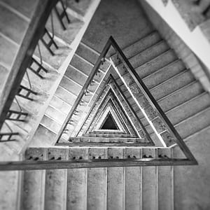 triangular spiraling staircase in grayscale photography thumbnail