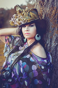 woman in purple polka-dot shirt leaning against tree at daytime thumbnail