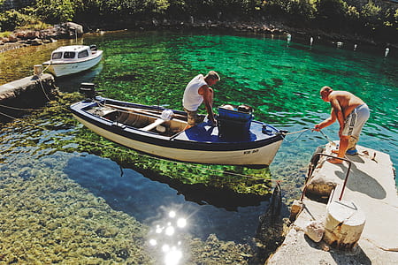 man standing on boat with body of water thumbnail