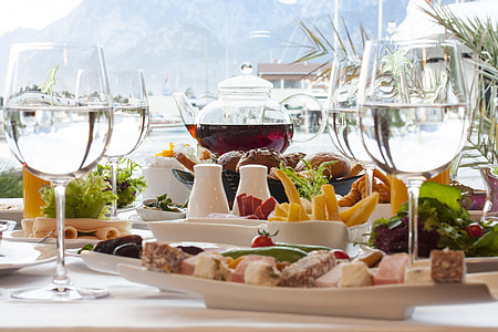 wine glasses near plates with variety of foods thumbnail