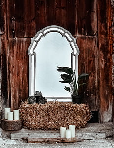 beveled mirror on hay beside pillar candles thumbnail