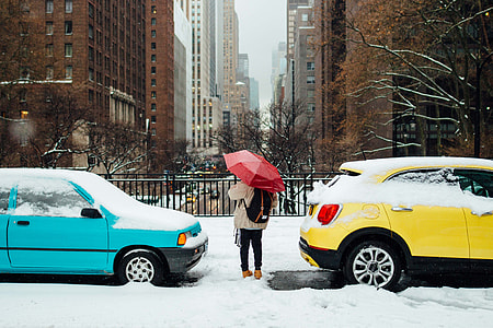 person holding red umbrella between cars thumbnail