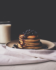 food photography of pancake top with blueberries on white ceramic plate beside a glass of milk thumbnail