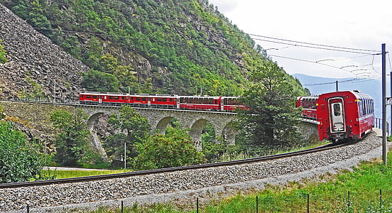 train traveling beside body of mountain thumbnail