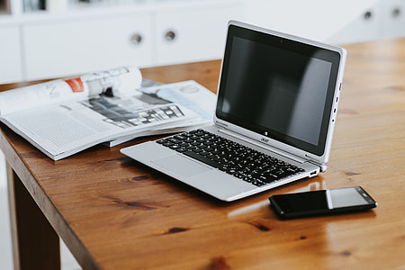 Silver laptop with various items on a table thumbnail