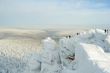 people standing on top of snow covered mountain facing snow covered trees thumbnail