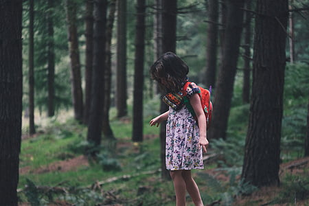 girl carrying orange backpack in forest during daytime thumbnail