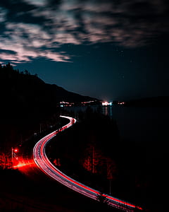timelapse photography of road near body of water at nighttime thumbnail
