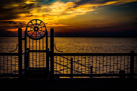 silhouette of fence in front of body of water thumbnail
