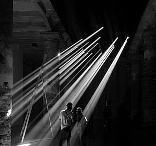 grayscale photography of two person standing on the ray of sun light thumbnail