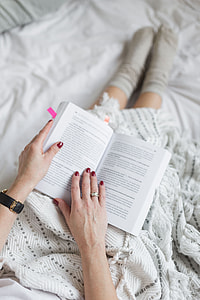 Soft photo of woman on the bed with the book and cup of coffee in hands thumbnail