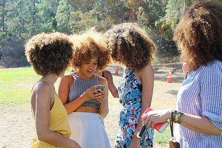 four women with brown afro hairs standing in grass field at daytime thumbnail