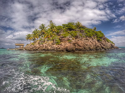 brown and green island under cloudy blue sky thumbnail