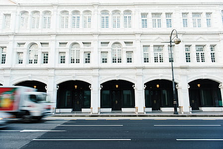 white and red box truck travelling on road near white building thumbnail