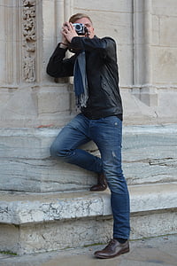 man leaning on white wall using DSLR camera thumbnail