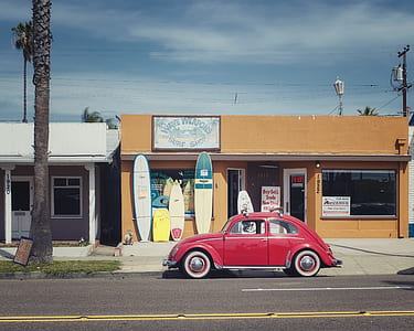 red Volkswagen Beetle on road near store at daytime thumbnail