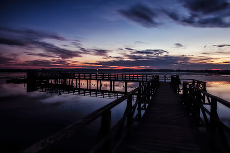 sea dock over calm body of water at sunset thumbnail