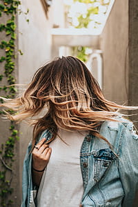 woman in blue denim button-up jacket covering her face with hair thumbnail