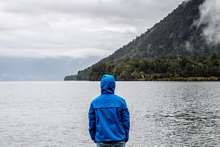 Person Wearing Blue Hoodie Near Body of Water thumbnail
