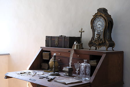 brown wooden analog clock on top of brown wooden slant-top desk near the wall thumbnail