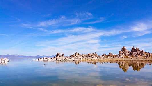 rock formation between body of water and blue sky thumbnail