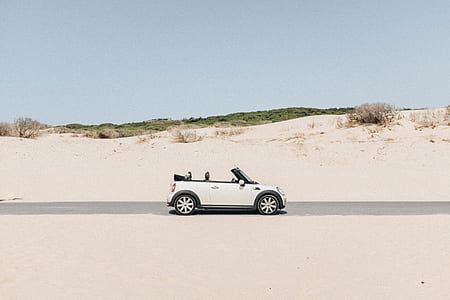 white Mini Cooper 3-door hatchback on road with an open roof under gray skies thumbnail