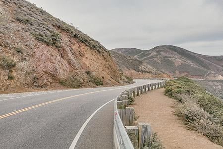gray concrete road with fences near rock formation thumbnail