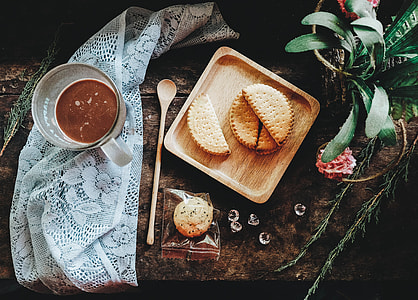sliced cookies on brown wooden plate beside clear mug on gray lace textile thumbnail