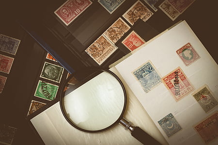 assorted-color postage stamp collection near magnifying glass on table thumbnail